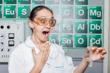 Excited woman looking at the test tube in the lab