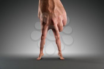 Male hand with legs instead of fingers over grey
