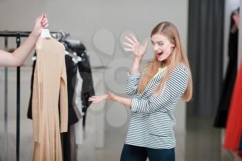 Excited woman looking at the dress prepared by shop assistant