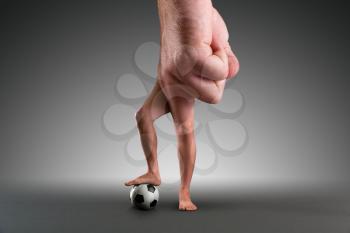 Male hand with legs instead of fingers playing football