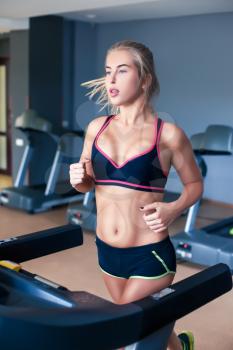Young girl training in the gym on the treadmill