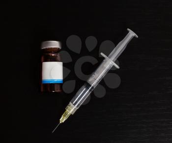 Syringe and bottle kit isolated on black background.