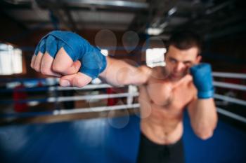 Boxer in blue wrist wraps on the training. Boxing ring on the background. Boxing power.