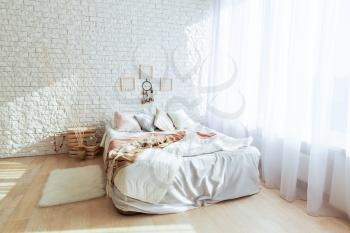 Minimalist white bedroom with big bed and brick wall. All in white colors. Bedroom interior concept. 