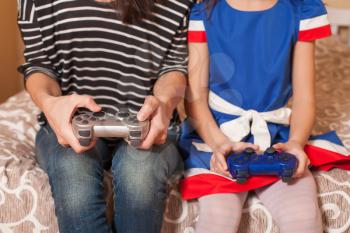 Closeup woman and female child playing game console.