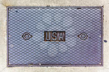 USA lettering on a steel manhole cover. Rectangular hatch cover with USA inscription and cell texture.