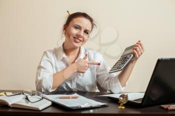 Happy young female accountant with calculator has reduced balance