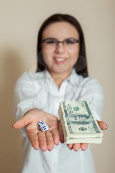 Young woman in glasses shows dollars and dice.