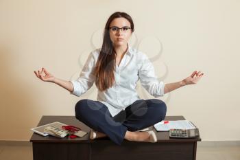 Female accountant sitting in yoga pose on the table in office