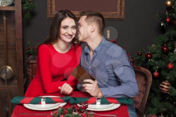 Young man gives a gift to beautiful woman. Love couple at luxury restaurant. Romantic date