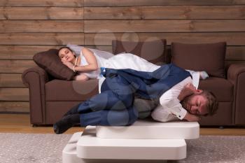 Tired bride and groom are sleeping on couch after wedding celebration