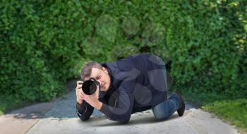 Male squat photographing on digital camera with professional lens