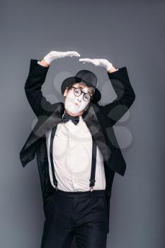 Male mime actor fun mimic performing. Pantomime in suit, gloves, glasses, make-up mask and hat. April fools day concept