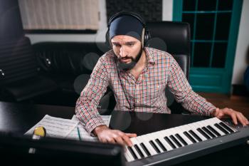 Sound producer in headphones work with musical keyboard in studio. Professional digital audio recording technology