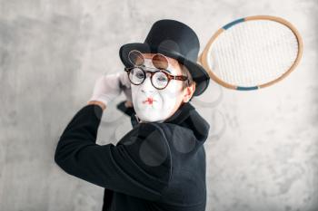 Pantomime actor performing with badminton racket. Comedy mime artist in suit, gloves, glasses, make-up mask and hat
