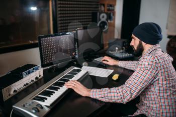 Audio engineer work with musical keyboard in studio. Professional digital sound recording technology