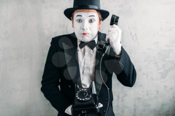 Pantomime theater actor with makeup mask performing with retro telephone. Comedy artist in suit, gloves and hat