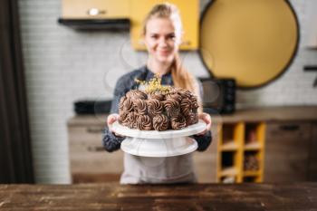 Woman cook shows chocolate cake, culinary masterpiece. Kitchen on background. Homemade sweet dessert