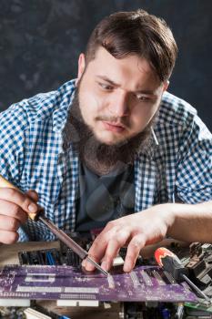 Repairman fixing problem with soldering tool. Engineer repairs computer components with soldering iron.
