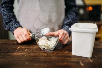 Female hands holds spoon with margarine over glass bowl. Sweet cake cooking preparation