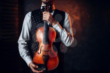 Portrait of male person holding wooden violin. Fiddler with musical instrument