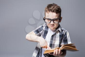 Strict boy in glasses with book in hands, studio photo shoot. School education concept