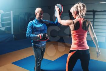 Womens self-defense workout with personal trainer, fighting training in gym, martial art