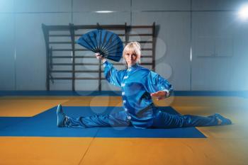 Female wushu master exercise with fan, martial arts. Woman in blue cloth on fight training