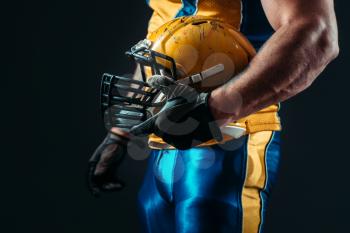 Muscular player with american football helmet in hand. Contact sport