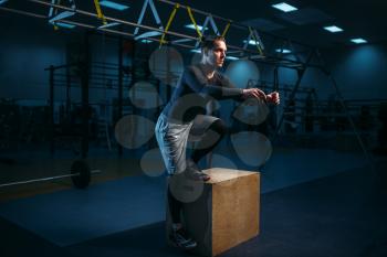 Athlete on training, endurance exercise with box in gym. Energy workout in sport club