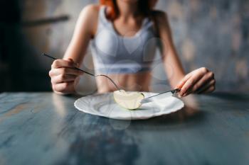 Female person against plate with a slice of apple. Weight loss diet concept