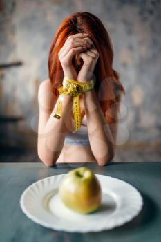 Womans hands are tied with measuring tape against plate with apple. Fat or calories burning concept. Weight loss