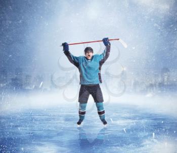 Professional ice hockey player hands up, snowy cityscape on background. Ice-skating outdoors