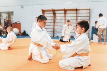 Little boys in uniform practice kid judo. Young fighters on training in gym, martial art for defense