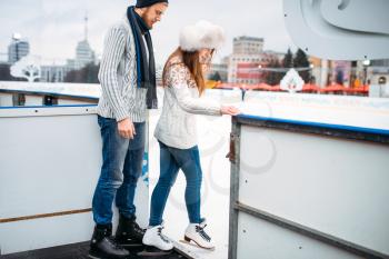 Love couple prepares to skate on the rink. Winter skating on open air, active leisure, ice-skating