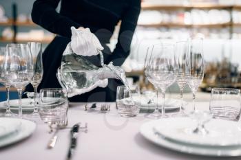 Waitress in gloves pours drinks into glasses, table setting. Serving service, festive dinner decoration