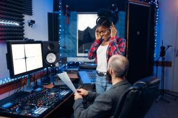 Sound operator and female singer at remote control panel in audio recording studio. Musician at the mixer, professional music mixing