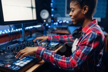 Female sound engineer working at the remote control panel in the recording studio.  Musician at the mixer, professional audio mixing