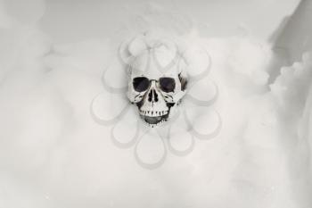 Scary human skeleton lying in the bathtub in foam, black humor, joke or surprise