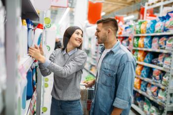 Couple in department of household chemicals, goods on shelves in supermarket, family shopping. Customers in shop, buyers in market