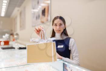 Cute female seller with shopping bags in jewelry store. Salewoman holds decorative cardboard packages in jewellery shop