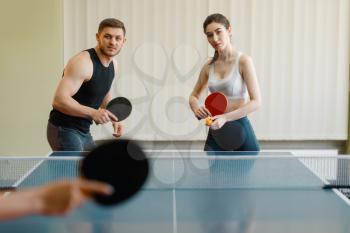 Friends playing sport game, group ping pong indoors. People in sportswear holds rackets and plays table tennis in gym