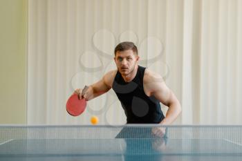 Man with racket and ball playing ping pong indoors. Male person in sportswear, training in table tennis club