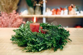 Christmas wreath with red burning candle closeup view, nobody. Holiday symbol, circle fir tree branch and candlelight, advent decoration, xmas celebration