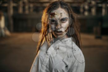 Female zombie walking in abandoned factory, scary place. Horror in city, creepy crawlies attack, doomsday apocalypse, bloody evil monster
