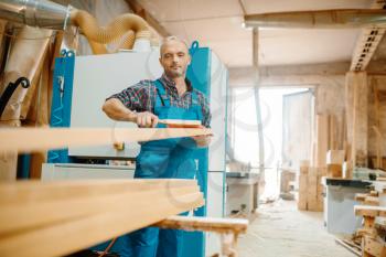 Carpenter processes board on plane machine, woodworking, lumber industry, carpentry. Wood processing on furniture factory, production of products of natural materials