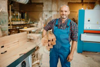 Carpenter holds stack of wooden beams, woodworking, lumber industry, carpentry. Wood processing on furniture factory, production of products of natural materials