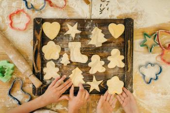 Two little girls chefs spread out cookies on a wooden board, bakery preparation on the kitchen, funny bakers. Kids cooking pastry and having fun, children cooks preparing cake