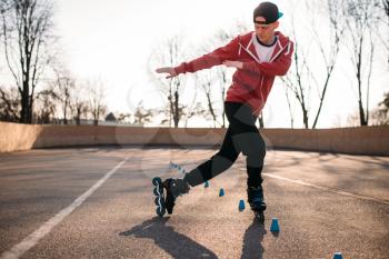 Roller skater rides the snake, rollerskating speed exercise in park. Male rollerskater leisure on sidewalk