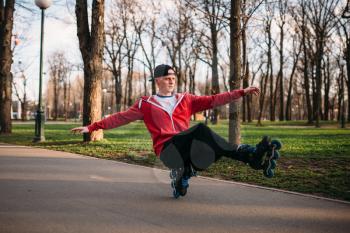 Roller skater doing balance exercise on sidewalk in city park. Male rollerskater leisure